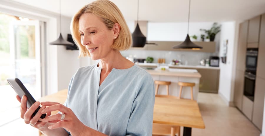 Woman holding a mobile device in a room filled with sunlight